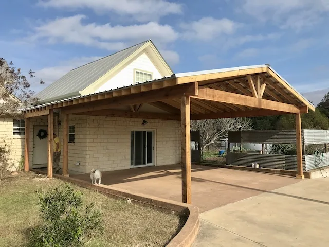Freestanding gable-roof dual-use pavilion and carport over a concrete driveway