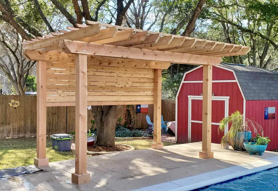 Unstained freestanding cedar pergola with a partial privacy and shade wall