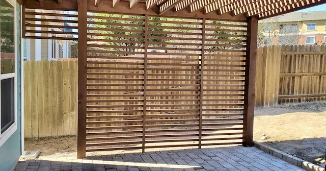 Cedar pergola with a 2-inch spaced wall for partial privacy and shade, stained to match