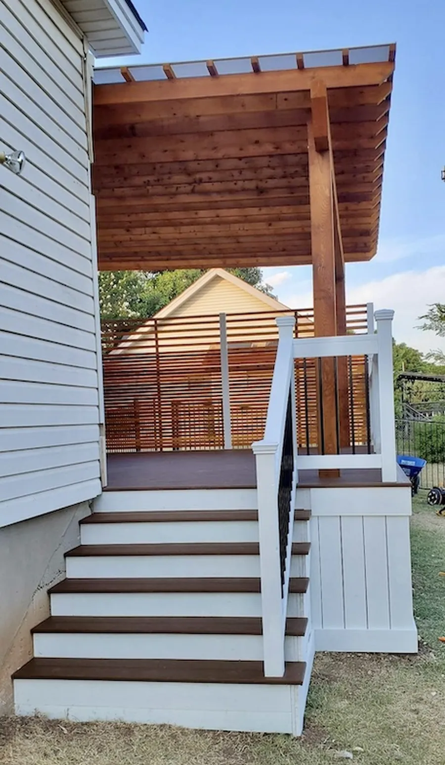 Trex deck with matching steps, cedar pergola, privacy wall, and tongue and groove skirting with under-deck storage