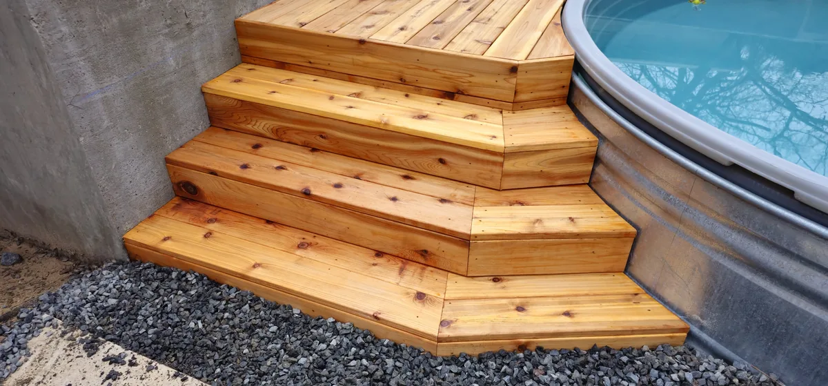 Custom-shape cedar deck with steps built around a stock tank cowboy pool