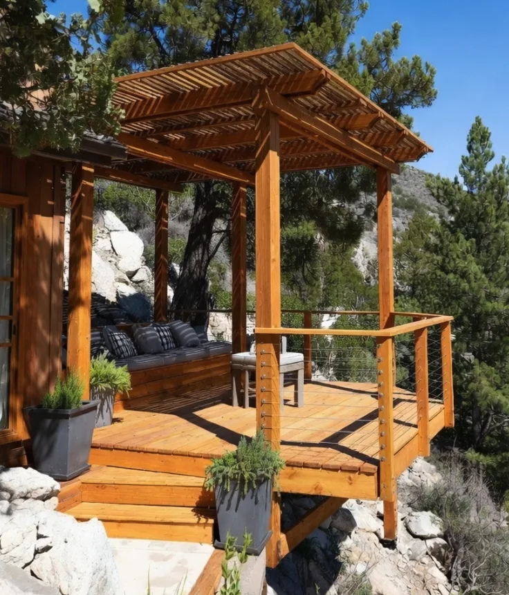 Pine deck and cedar pergola on a rocky mountain lot, stained to match, with cable railing and steps