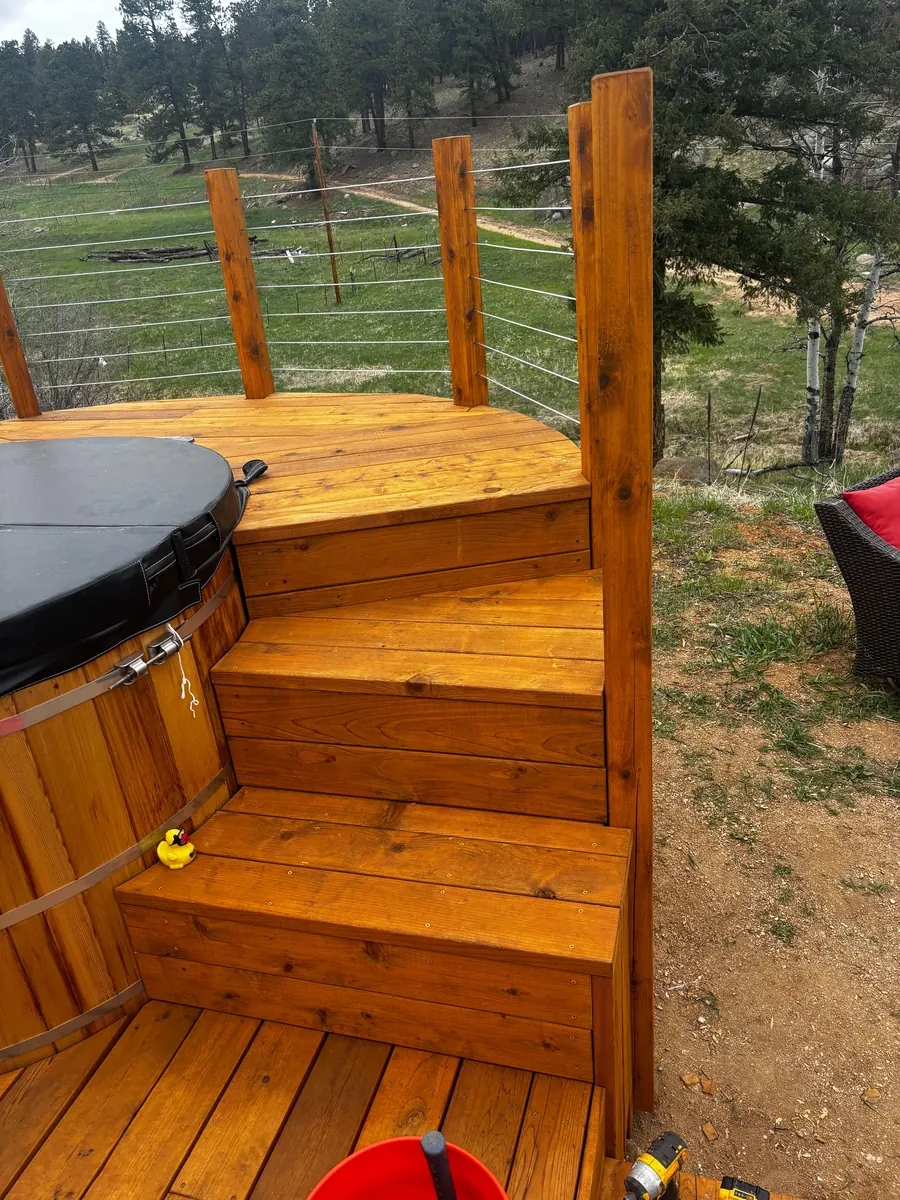 Deck with staircase built around a hot tub on a Colorado mountain property
