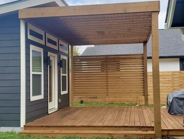 Modern attached cedar pergola with a slatted privacy wall over a cedar deck, stained to match